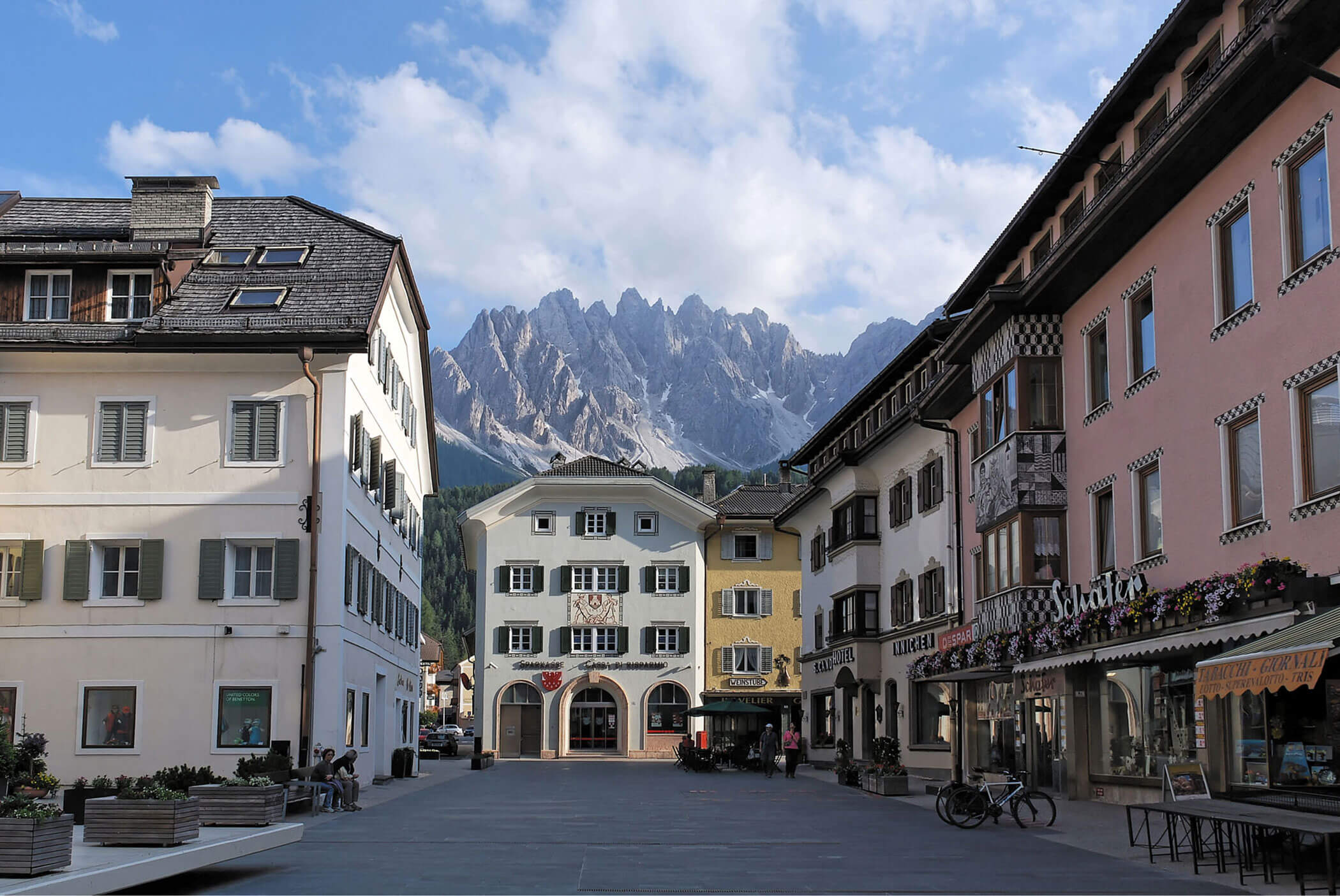 Ein ruhiger europäischer Stadtplatz mit Gebäuden im alpinen Stil und Bergen im Hintergrund. - Hotel Mooserhof